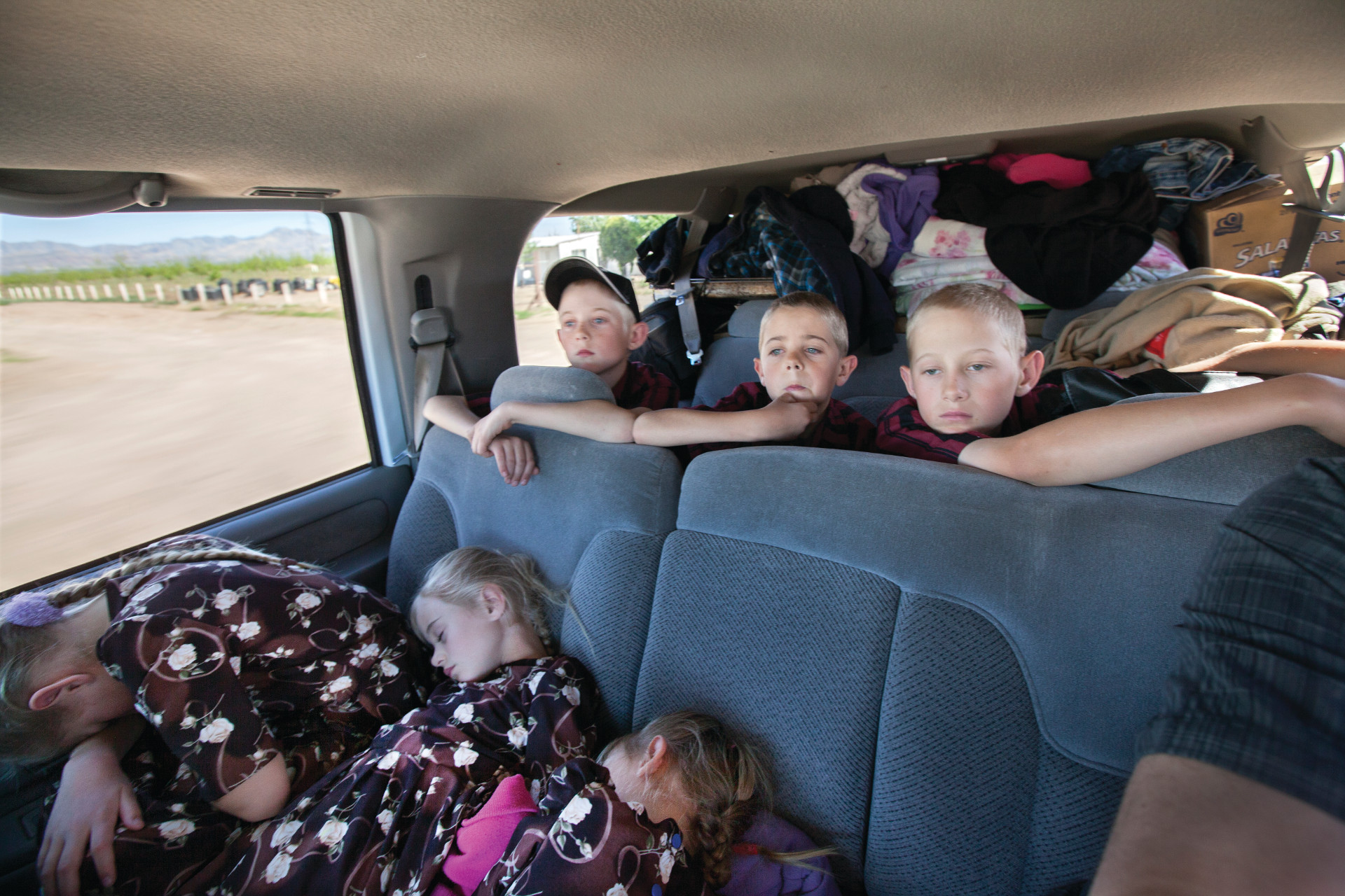 <small>The family prepares to leave the Mexican desert, the only home they’ve known. The car is packed with belongings and children.</small>