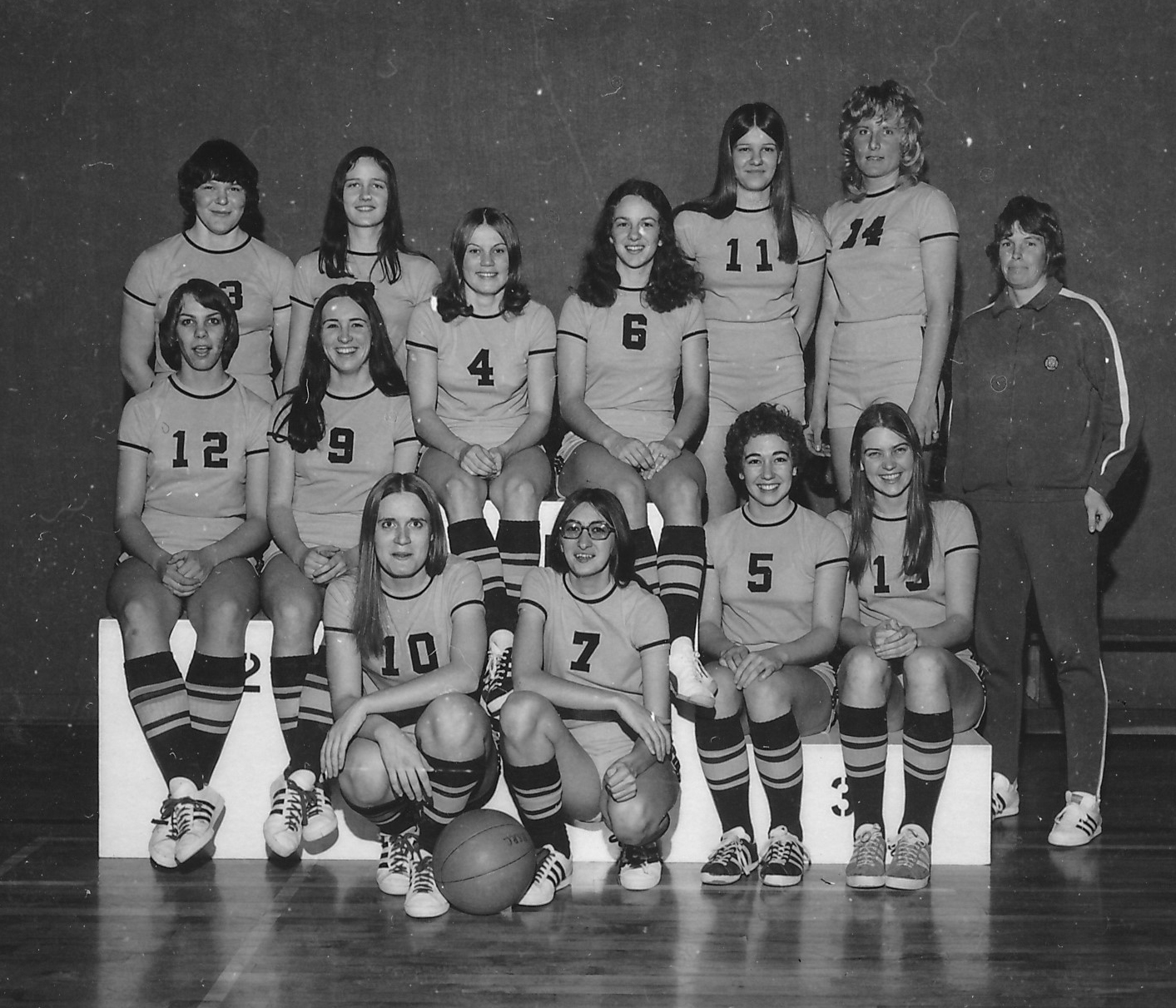 7475_wbb Smiling individuals in archival black and white image of women's basketball team.